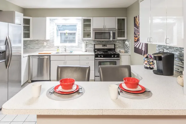 a kitchen with stainless steel appliances kitchen island granite countertop a stove and white cabinets