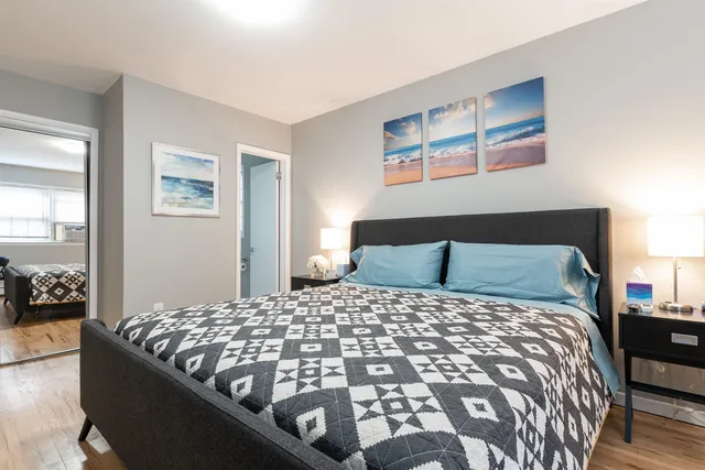 a bedroom with a large bed and a lamp on dresser