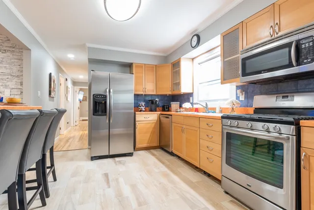 a kitchen with stainless steel appliances granite countertop a refrigerator a stove and a sink with cabinets