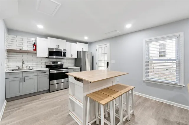 a kitchen with stainless steel appliances granite countertop a sink a stove a refrigerator cabinets and a window