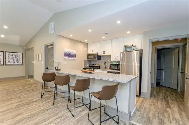 a kitchen with stainless steel appliances kitchen island granite countertop a refrigerator and a stove top oven