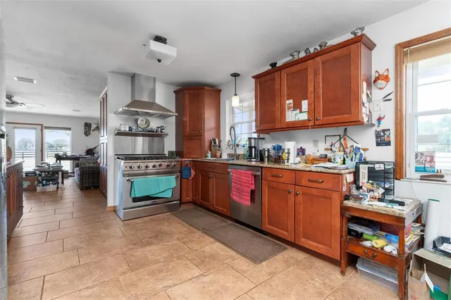 a kitchen with stainless steel appliances a refrigerator a stove a dining table and chairs with wooden floor