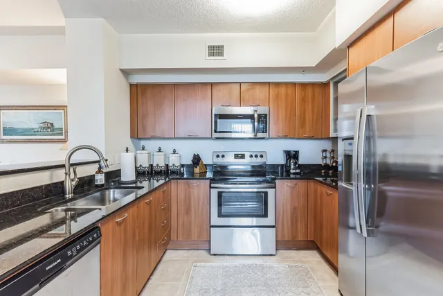 a kitchen with stainless steel appliances granite countertop a stove top oven a sink and a refrigerator