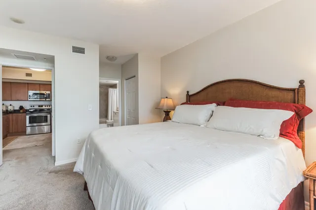 a spacious bedroom with a bed and a view of kitchen