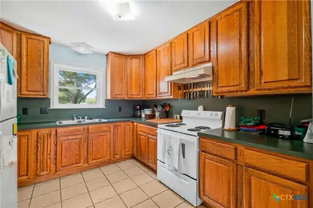 a kitchen with stainless steel appliances granite countertop a sink a stove cabinets and a window