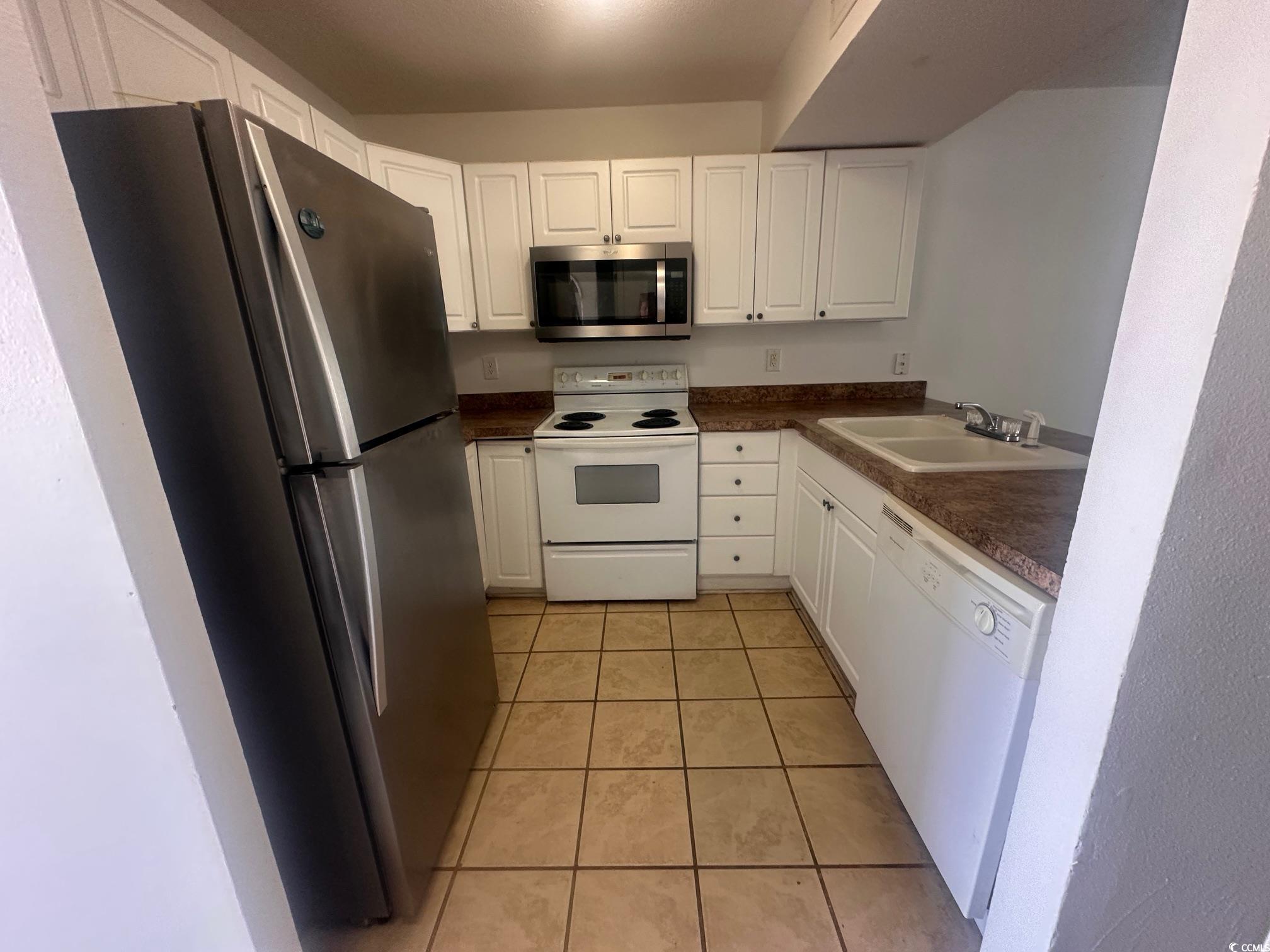 3555 Highway 544, Unit 27B Conway, SC 29526 - Photo 3 of 6 Kitchen featuring appliances with stainless steel finishes, dark countertops, light tile patterned floors, and white cabinetry