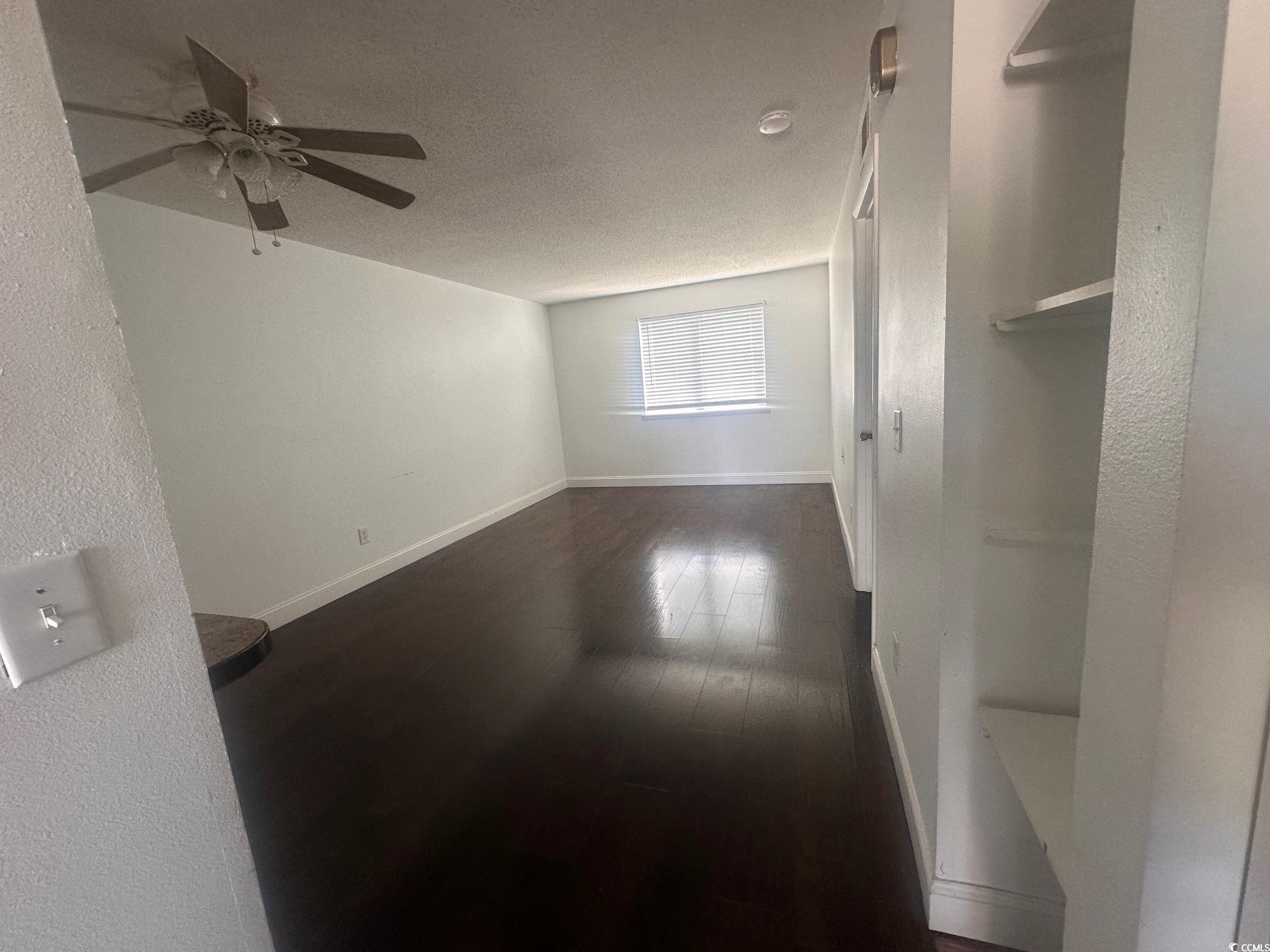3555 Highway 544, Unit 27B Conway, SC 29526 - Photo 4 of 6 Spare room featuring dark wood-type flooring, a textured ceiling, a textured wall, and ceiling fan
