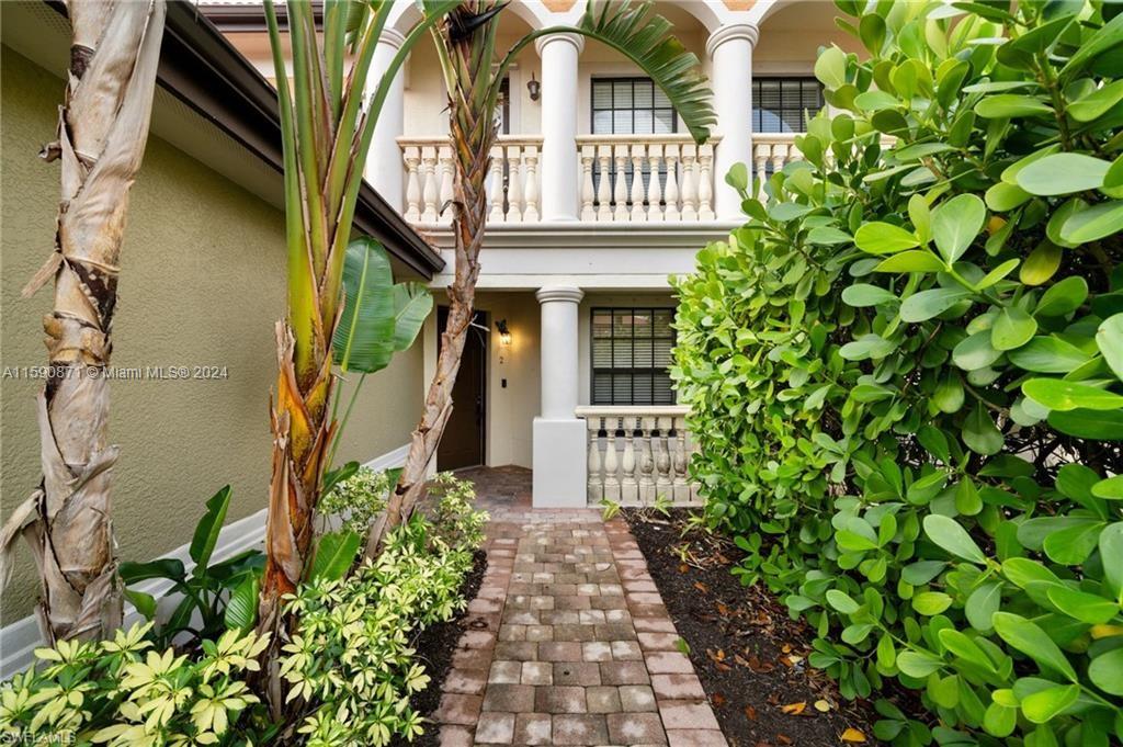 1276 Strada Milan Lane, Unit 2 Naples, FL 34105 - Photo 2 of 36 a pathway of a house with a fountain and a flower garden