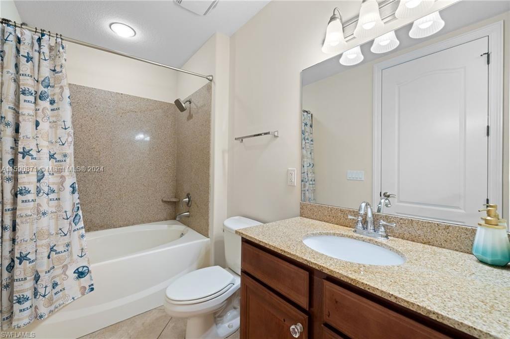 1276 Strada Milan Lane, Unit 2 Naples, FL 34105 - Photo 24 of 36 a bathroom with a granite countertop sink a toilet a mirror a bathtub and shower