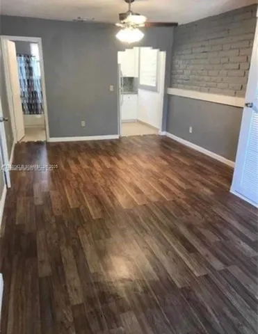 a view of an empty room with window and wooden floor