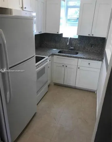 a kitchen with a refrigerator sink and cabinets