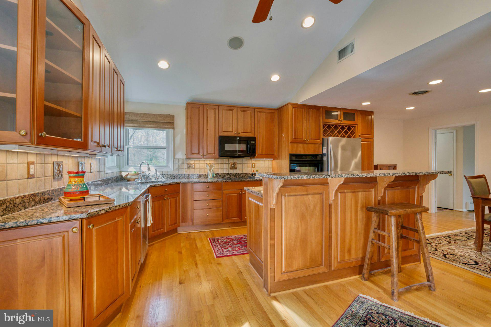 1100 Springvale Road Great Falls, VA 22066 - Photo 3 of 47 a kitchen with stainless steel appliances granite countertop a refrigerator a stove top oven and a sink with wooden floor