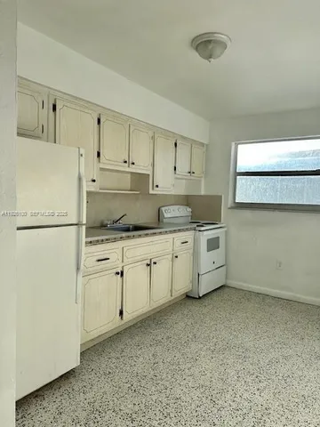 a kitchen with granite countertop white cabinets and refrigerator