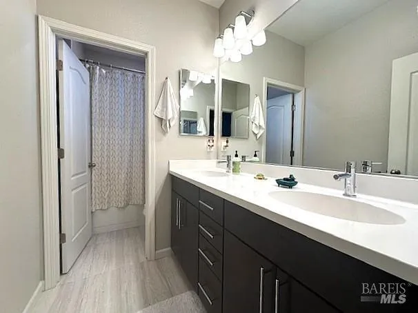 a bathroom with a double vanity sink a mirror a vanity and a bathtub