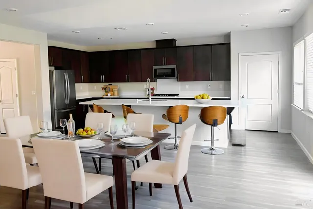 a kitchen with a dining table chairs and refrigerator