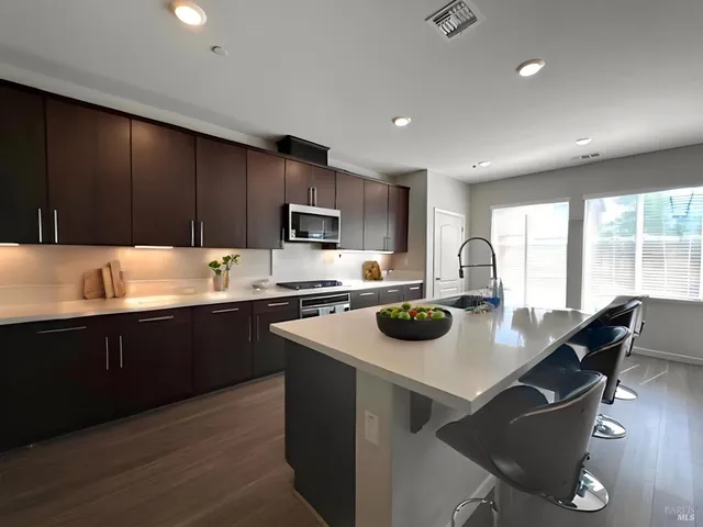 a kitchen with a stove a sink a microwave a dining table and chairs