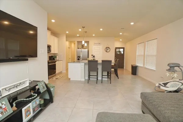 a living room with furniture a flat screen tv and kitchen view