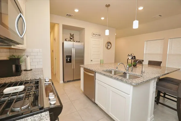 a kitchen with kitchen island granite countertop a sink stainless steel appliances and cabinets