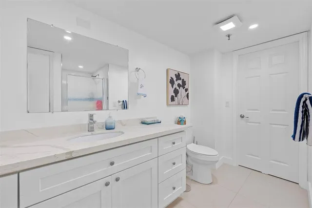 a bathroom with a granite countertop toilet sink and mirror