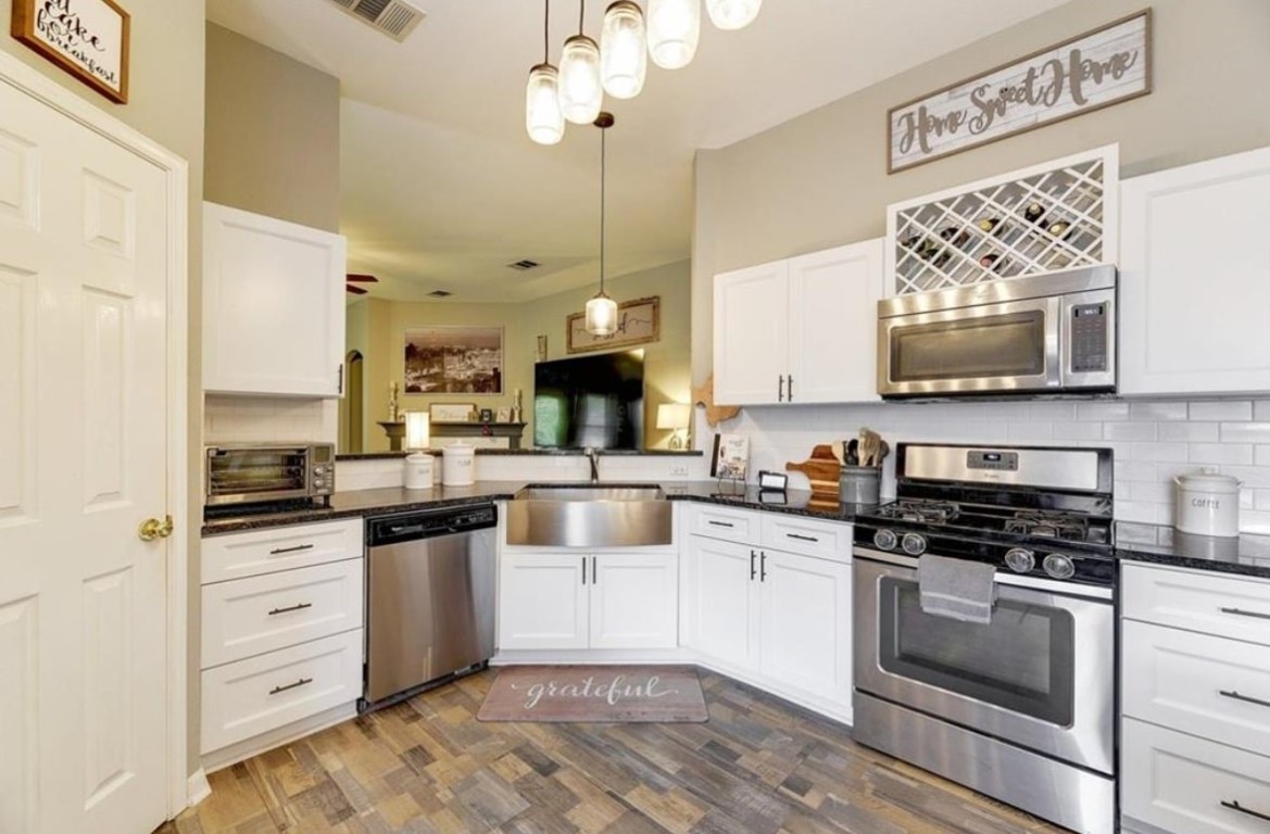 1307 Ridgewood Drive Leander, TX 78641 - Photo 7 of 16 a kitchen with stainless steel appliances white cabinets a stove a sink and a microwave