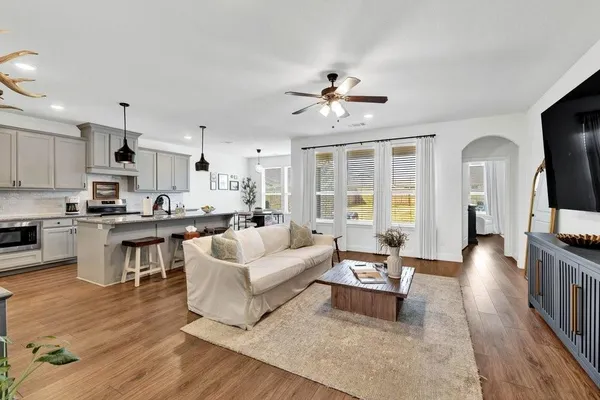 a living room with furniture kitchen view and a wooden floor