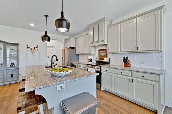 a kitchen with stainless steel appliances granite countertop a sink a stove and white cabinets