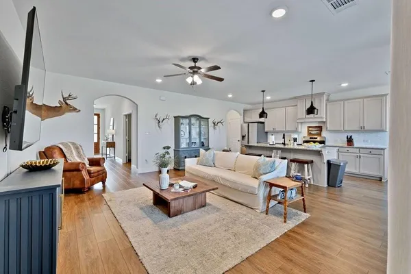a living room with furniture kitchen view and a chandelier