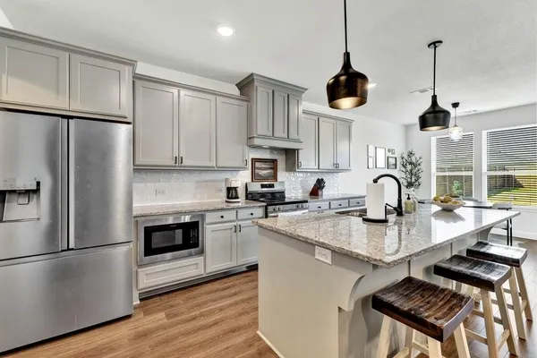 a kitchen with stainless steel appliances granite countertop a stove a refrigerator and a sink with wooden floor