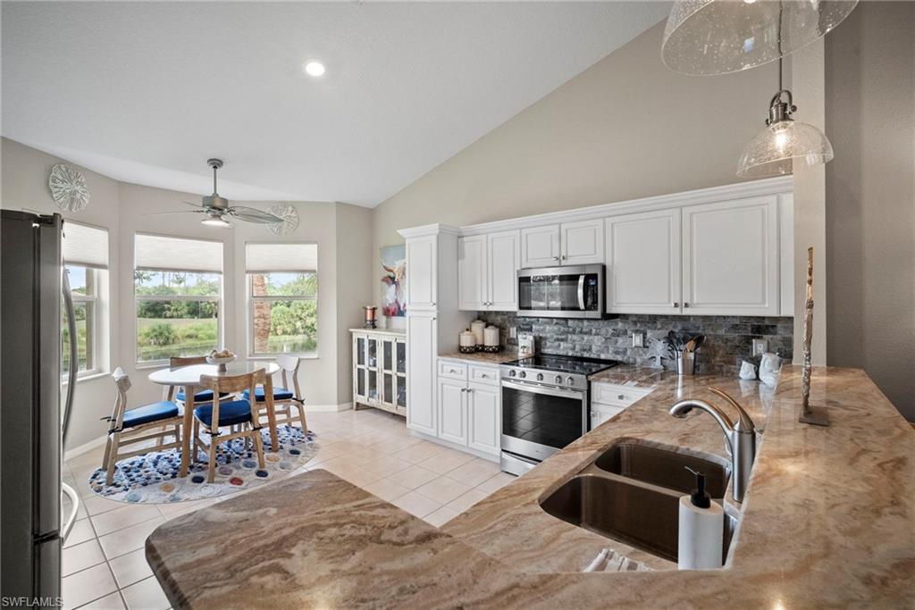 20051 Seagrove Street, Unit 1207 Estero, FL 33928 - Photo 14 of 32 a kitchen with stainless steel appliances granite countertop a stove top oven a sink dishwasher a dining table and chairs with wooden floor