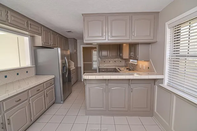 a kitchen with white cabinets and refrigerator