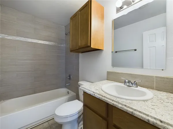 a bathroom with a granite countertop sink a toilet and bathtub