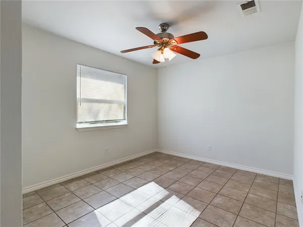 an empty room with windows and fan