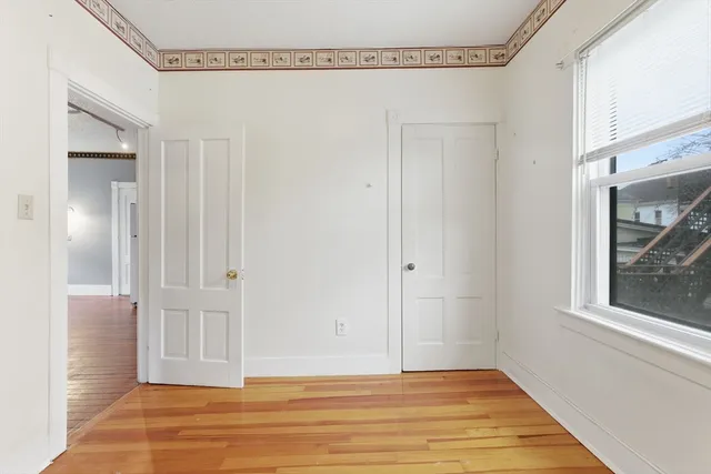 a view of empty room with window and wooden floor