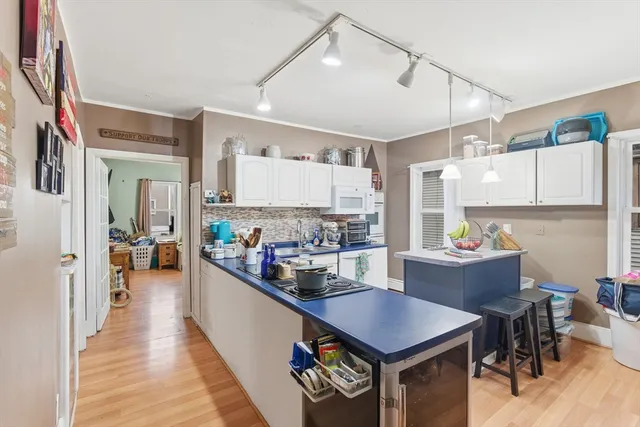 a kitchen with a stove a refrigerator and a dining table with wooden floor