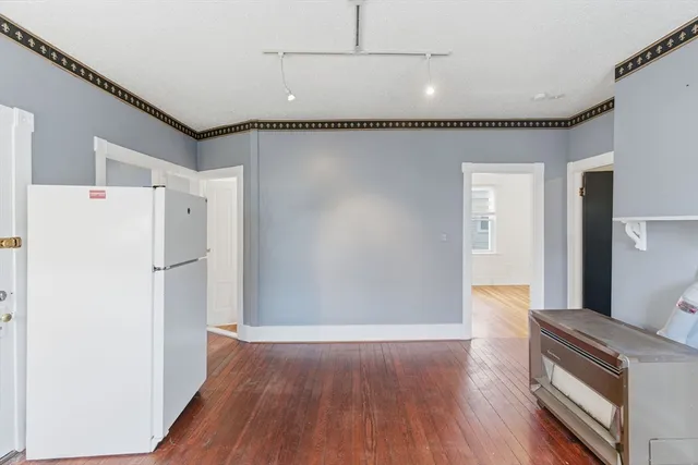a kitchen with a refrigerator and wooden floor