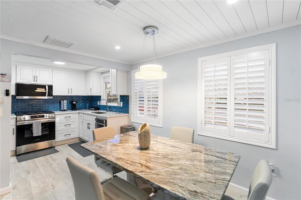 9022 Midnight Pass Road, Unit 112 Sarasota, FL 34242 - Photo 11 of 40 a large kitchen with kitchen island a stove a sink a refrigerator dining table and chairs