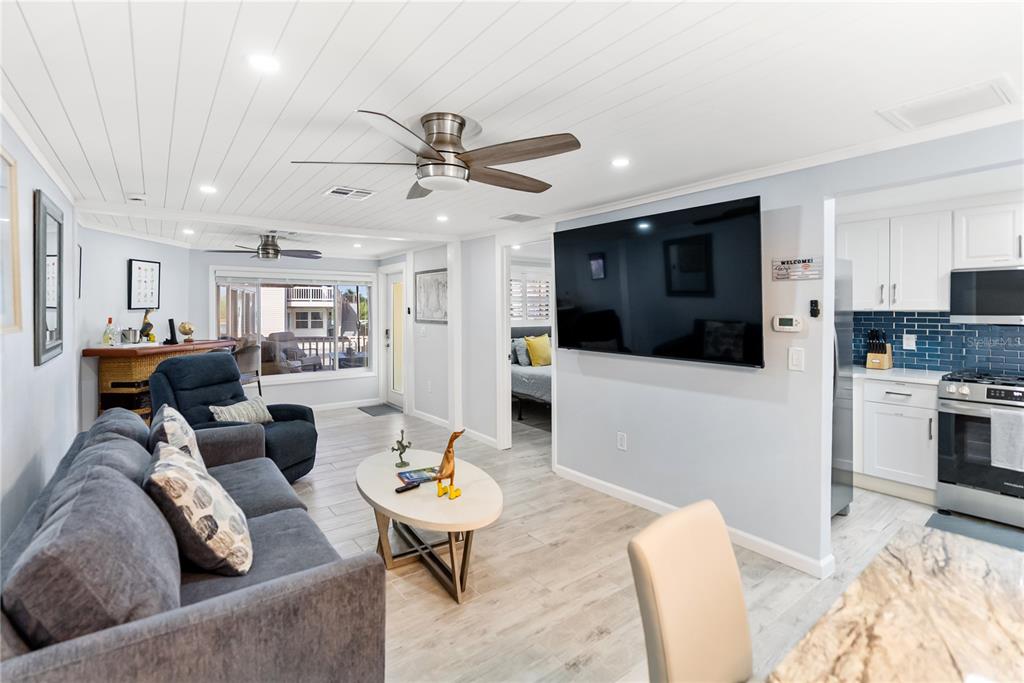 9022 Midnight Pass Road, Unit 112 Sarasota, FL 34242 - Photo 12 of 40 a living room with furniture kitchen view and a flat screen tv