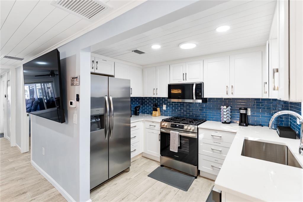 9022 Midnight Pass Road, Unit 112 Sarasota, FL 34242 - Photo 13 of 40 a kitchen with a sink a refrigerator and cabinets