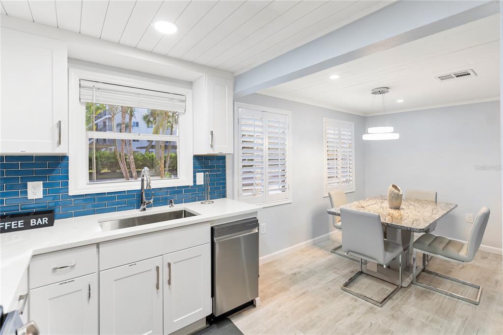 9022 Midnight Pass Road, Unit 112 Sarasota, FL 34242 - Photo 14 of 40 a kitchen with a sink chairs and white cabinets