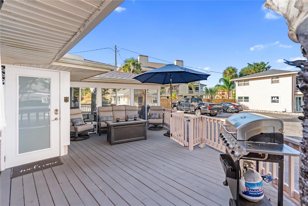 9022 Midnight Pass Road, Unit 112 Sarasota, FL 34242 - Photo 21 of 40 a view of a patio with table and chairs under an umbrella with wooden floor