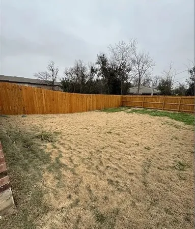 a view of a yard with wooden fence