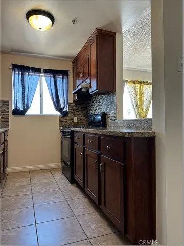 a view of empty room with wooden floor and kitchen
