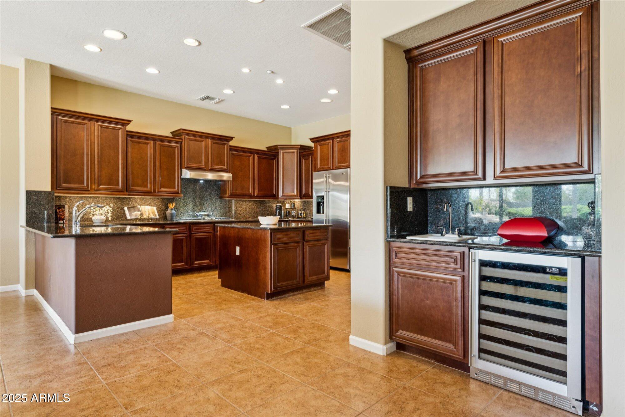 4959 North Village Road Litchfield Park, AZ 85340 - Photo 16 of 55 a kitchen with stainless steel appliances granite countertop a refrigerator sink and cabinets