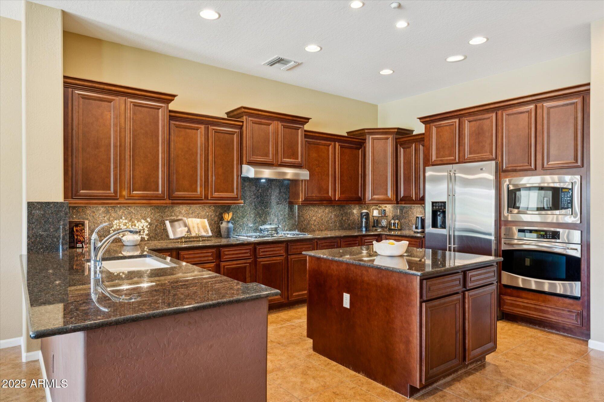 4959 North Village Road Litchfield Park, AZ 85340 - Photo 18 of 55 a kitchen with kitchen island granite countertop a sink counter top space appliances and cabinets