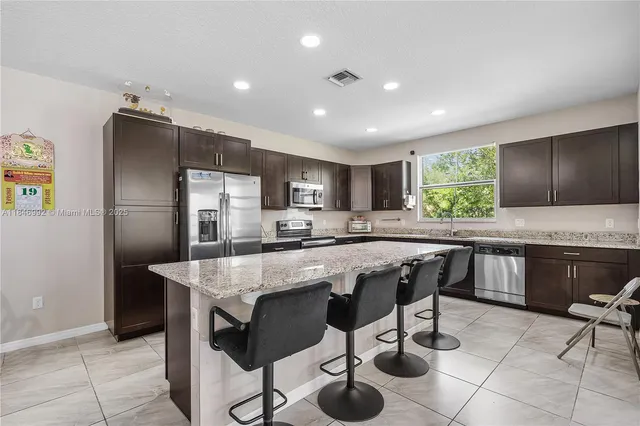 a kitchen with stainless steel appliances granite countertop a table chairs sink refrigerator and microwave