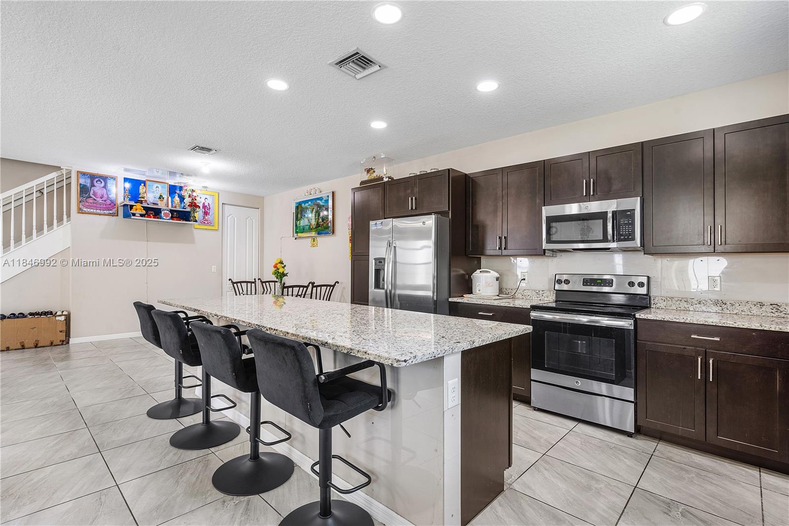 6411 Osprey Landing Street Davie, FL 33314 - Photo 16 of 38 a kitchen with stainless steel appliances granite countertop a stove a sink a microwave and a refrigerator
