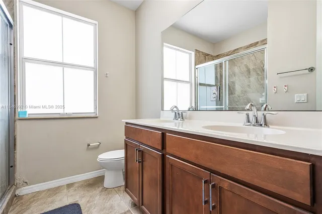 a bathroom with a granite countertop sink a toilet and a window