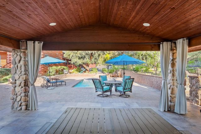 a view of a patio with table and chairs under an umbrella with a barbeque grill