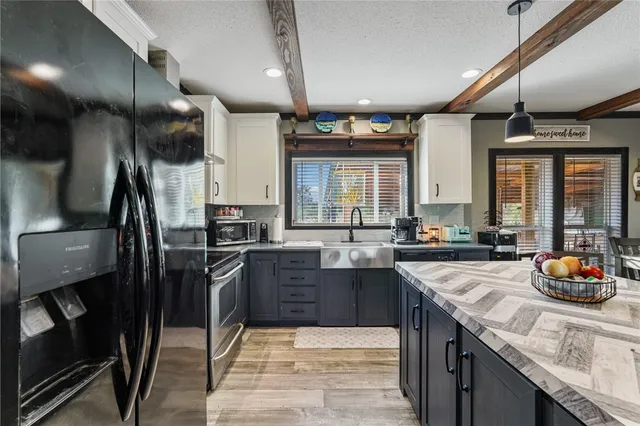 a kitchen with stainless steel appliances granite countertop sink stove refrigerator and cabinets