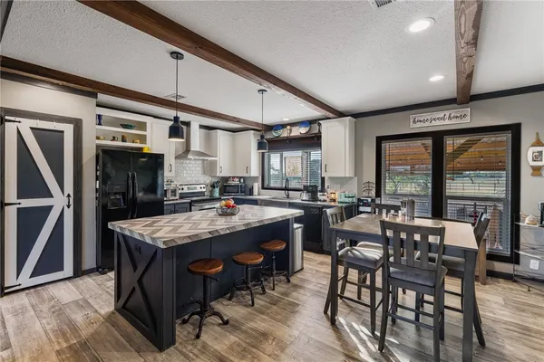a dining hall with stainless steel appliances granite countertop a stove a kitchen island a table and chairs